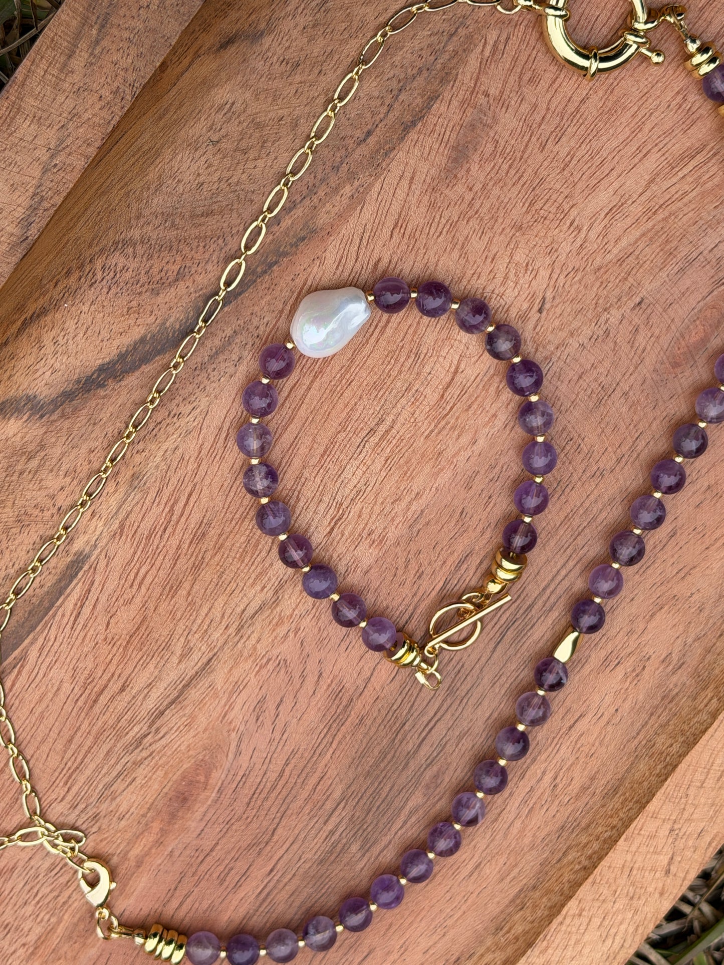 Amethyst beaded bracelet with gold chain on a wooden surface