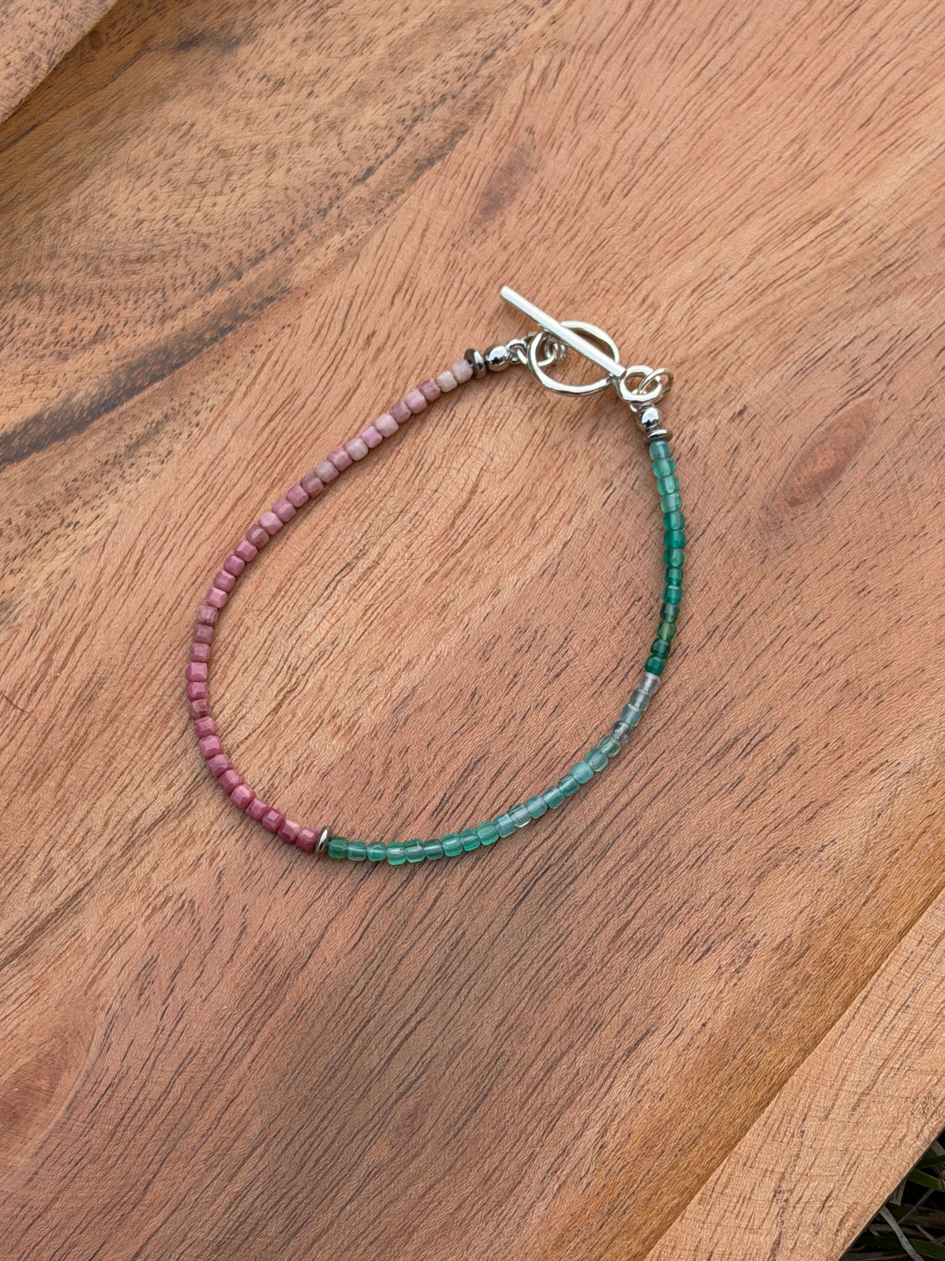 Beaded bracelet with green and purple beads on a wooden surface