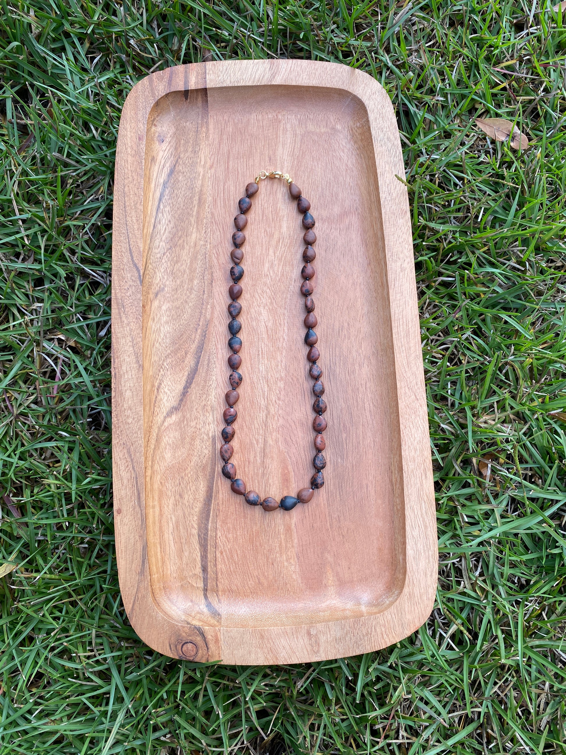 Wooden tray with a necklace on grass