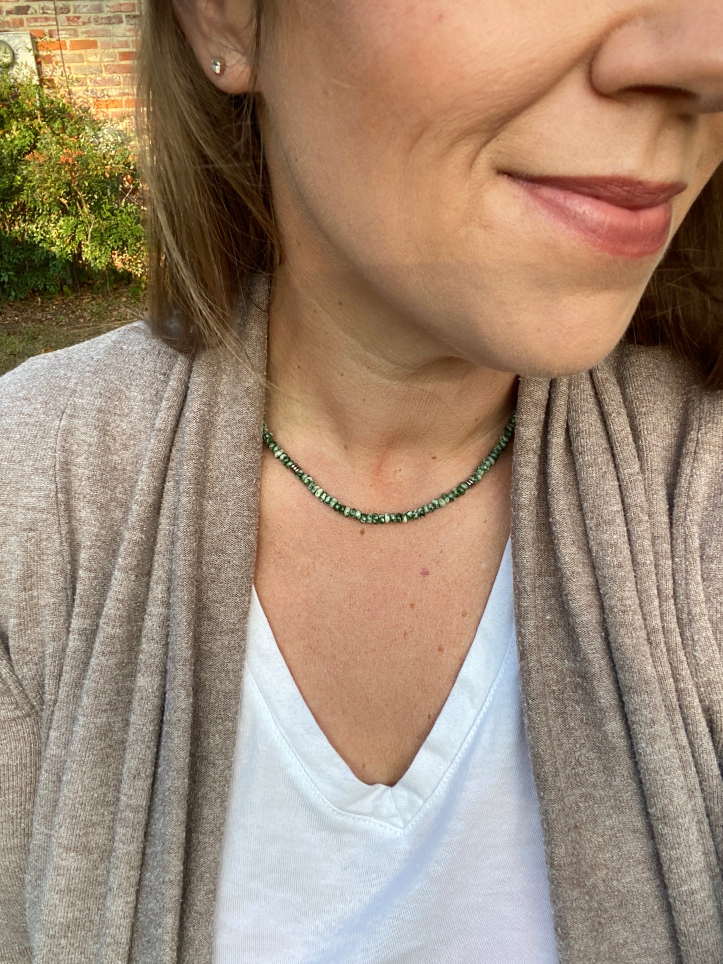 Close-up of a person wearing a green beaded necklace