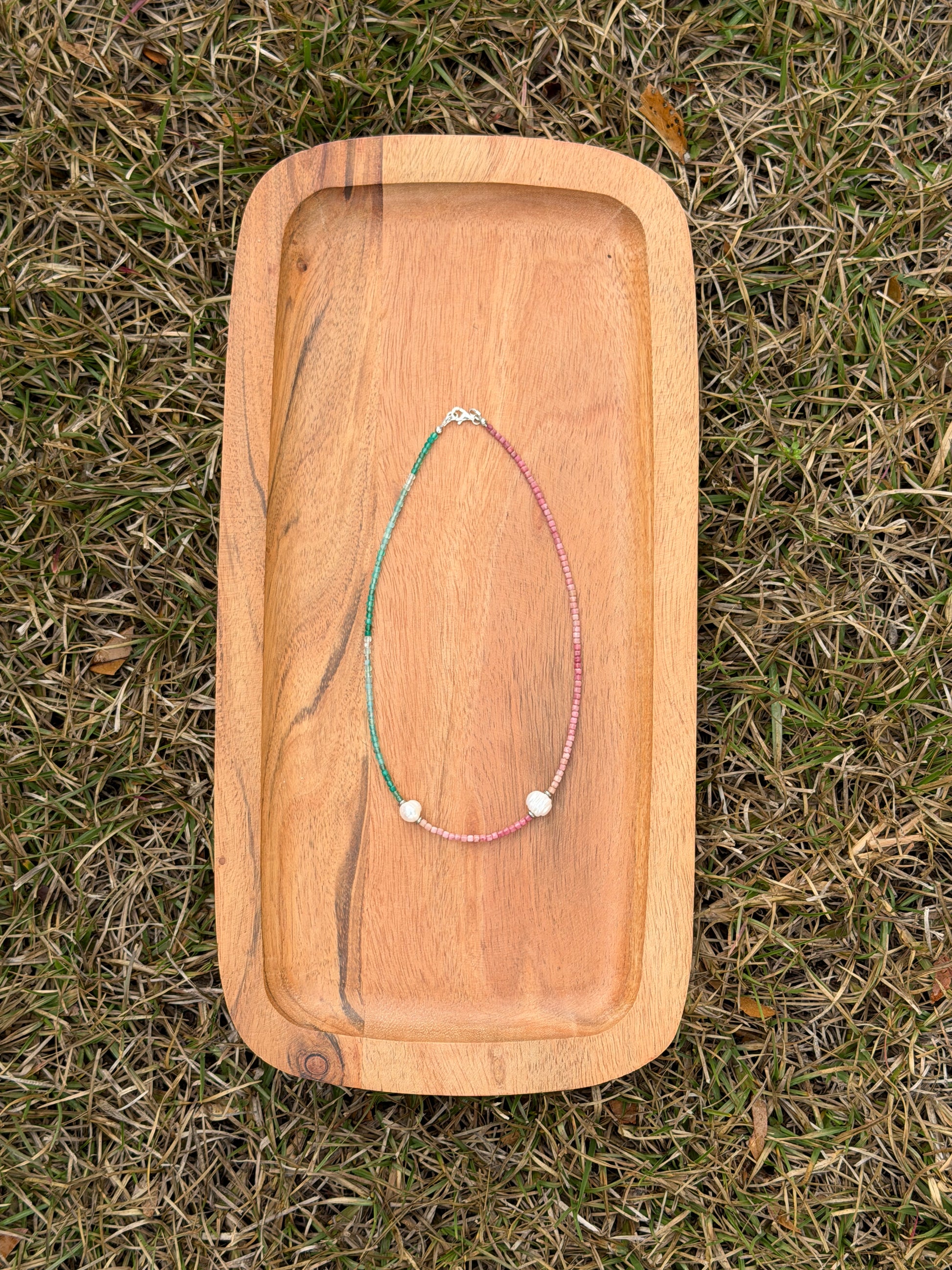 Wooden tray with necklaces on a grassy background