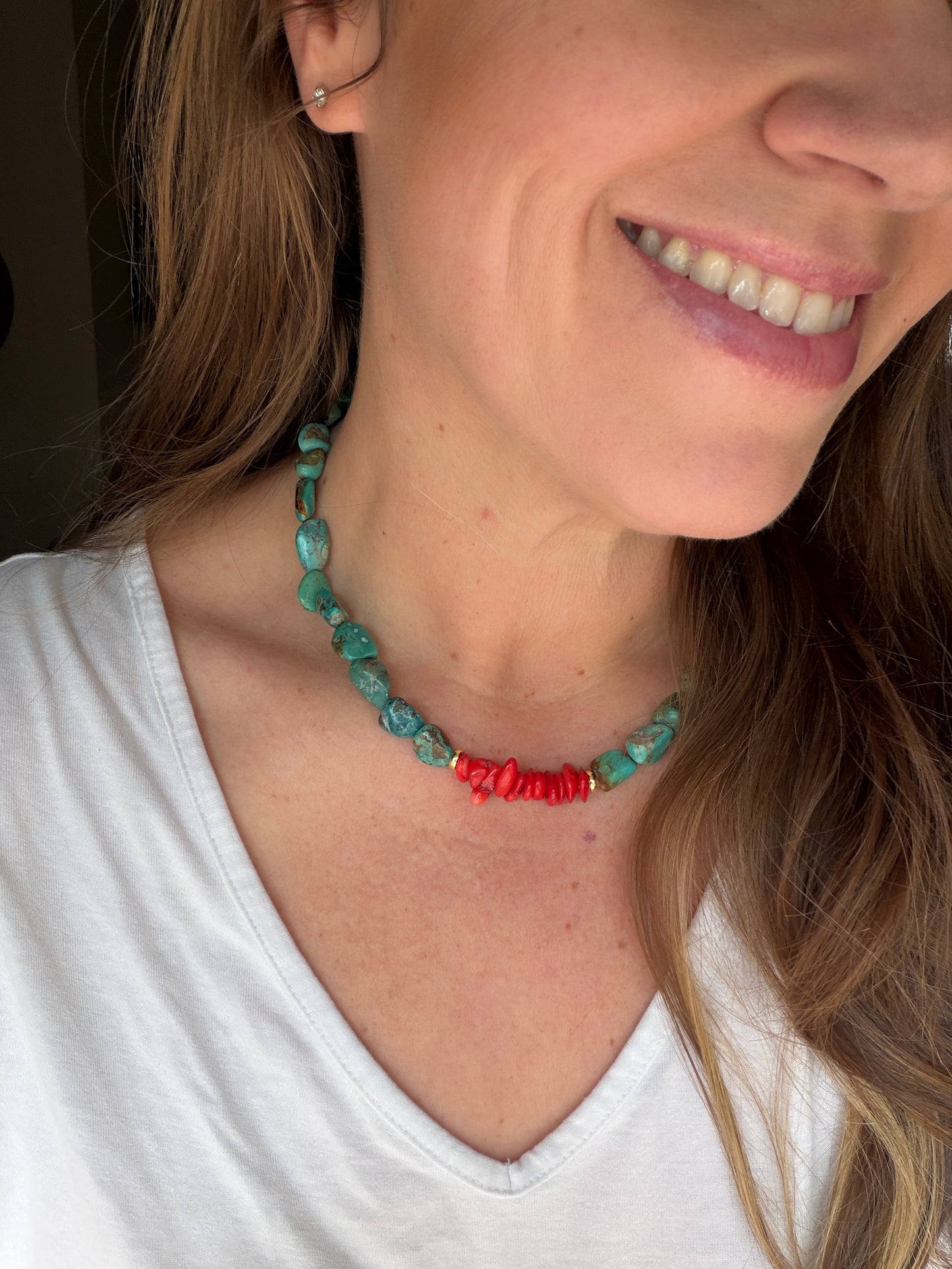 Woman wearing a colorful turquoise necklace with a plain background