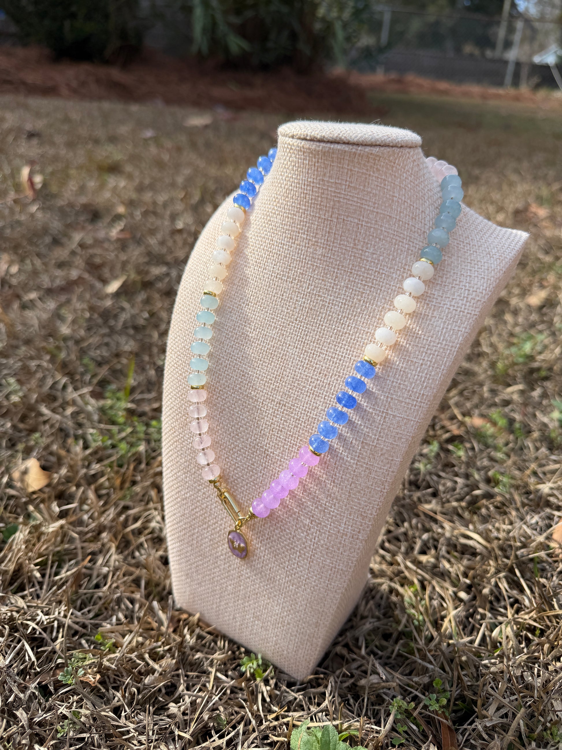 Multicolored beaded necklace on a beige fabric roll against a natural background