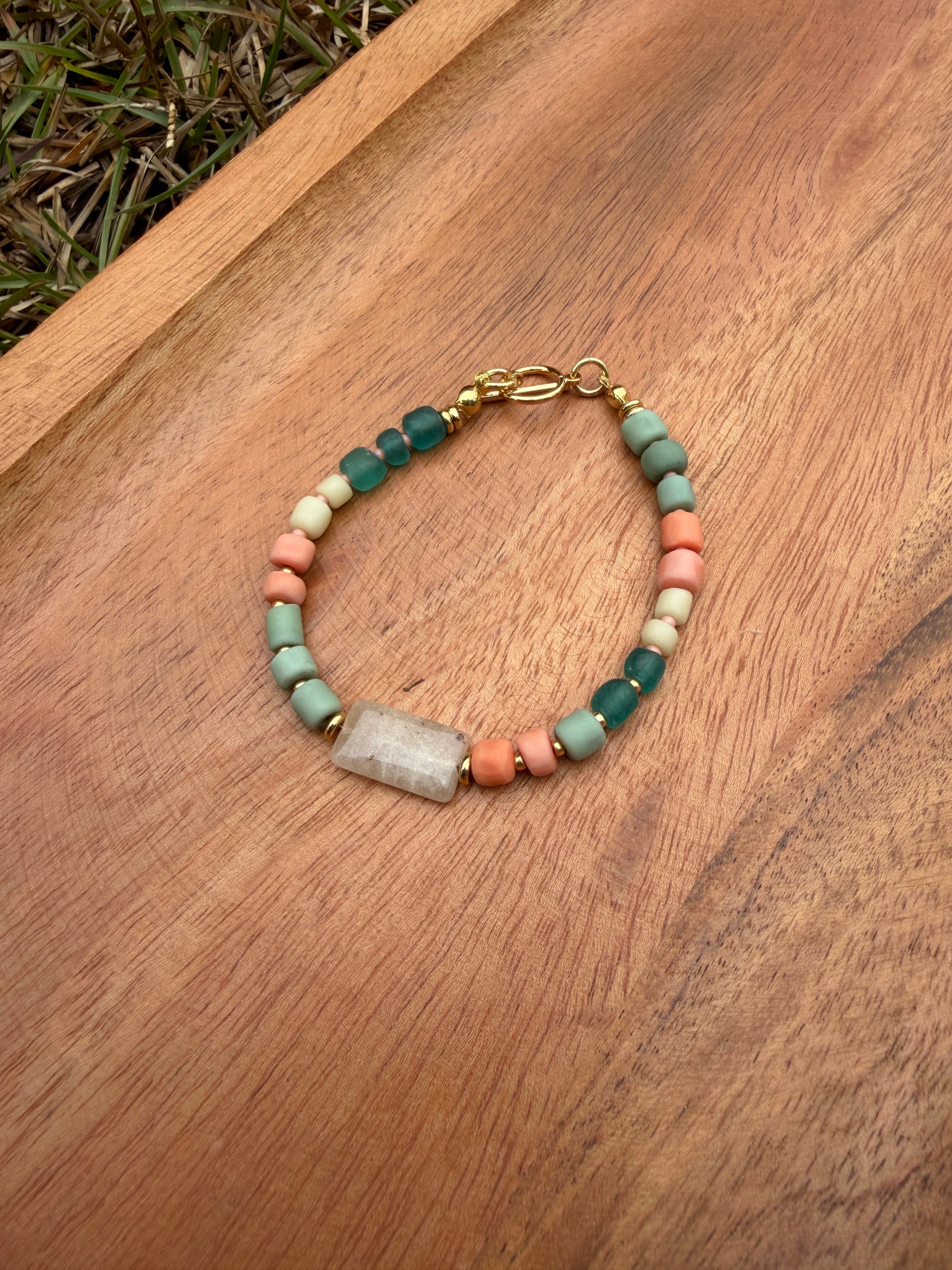 Beaded bracelet with a gold clasp on a wooden surface