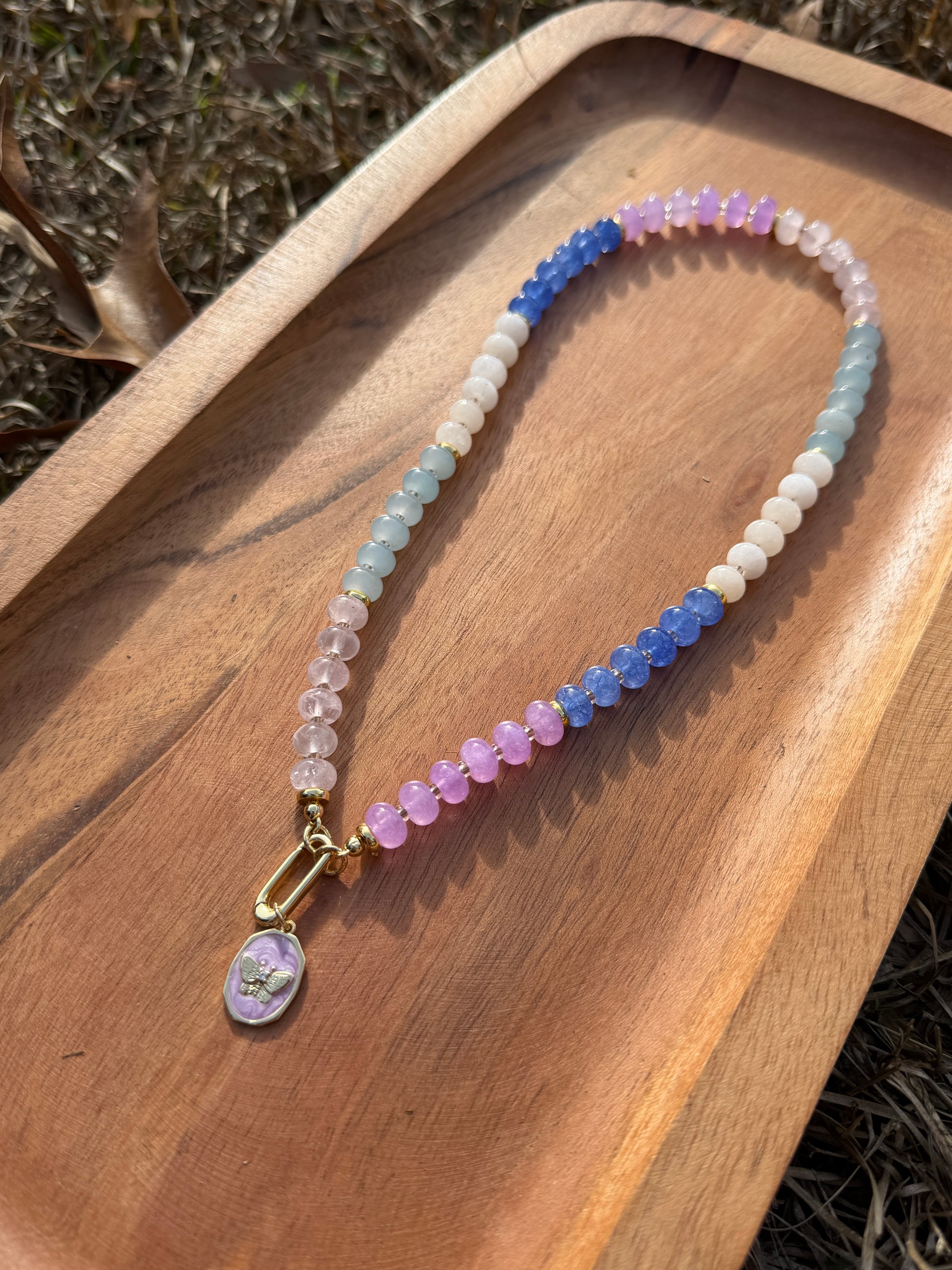 Beaded necklace with a gold clasp on a wooden surface