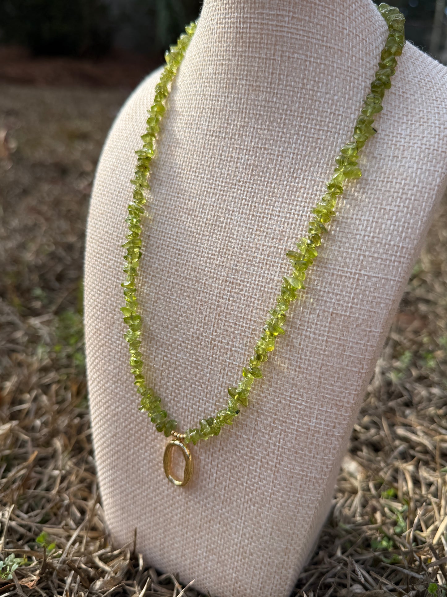 Green beaded necklace on a beige fabric surface with a natural background