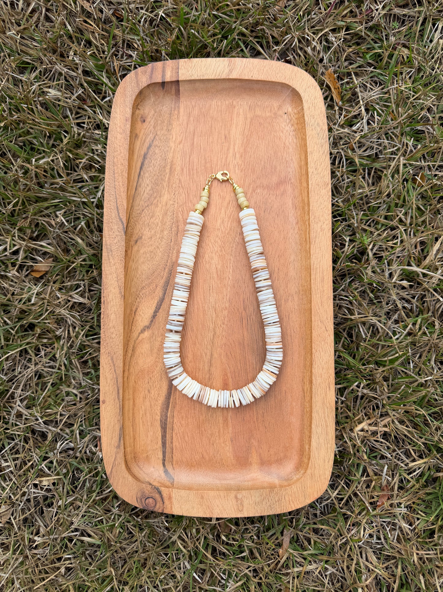 Wooden tray with a necklace on grass