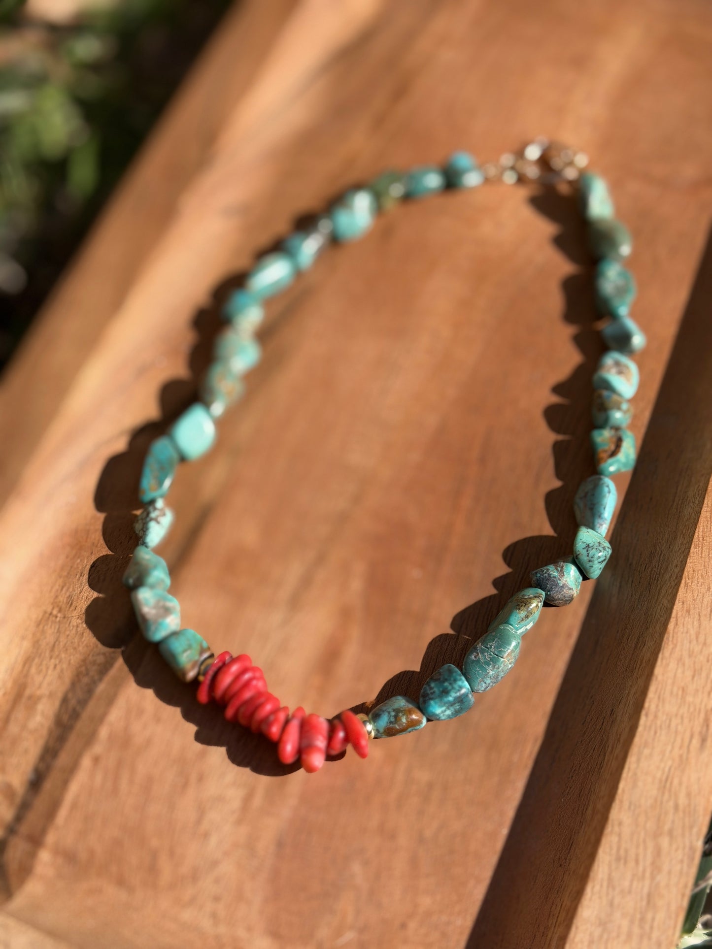 Necklace with turquoise and coral beads on a wooden surface