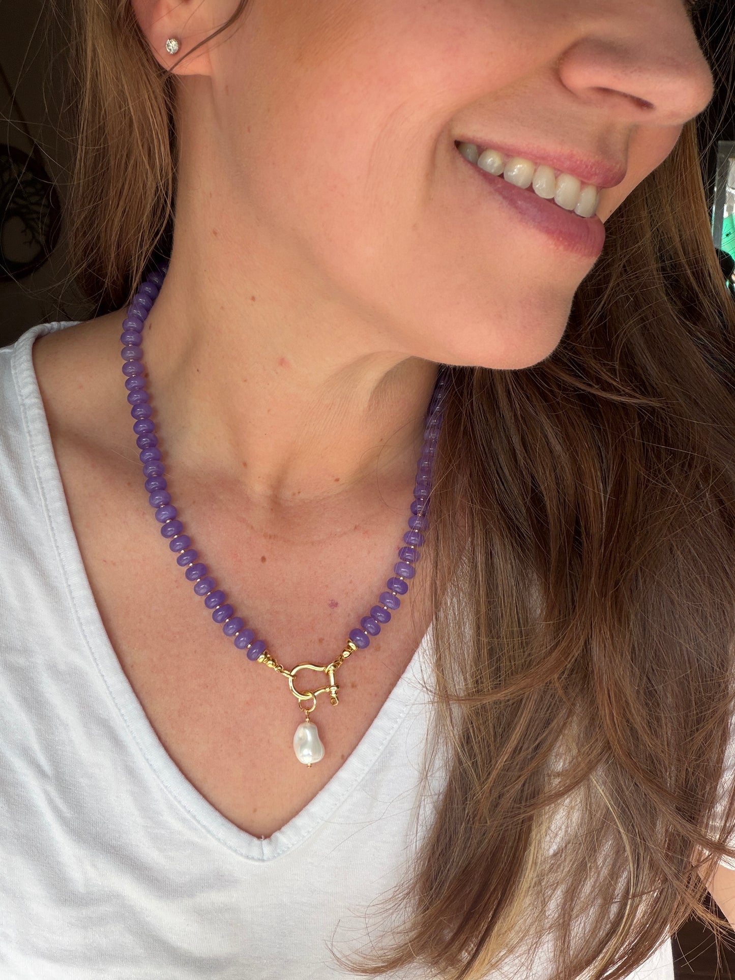 Woman wearing a purple beaded necklace with a white top