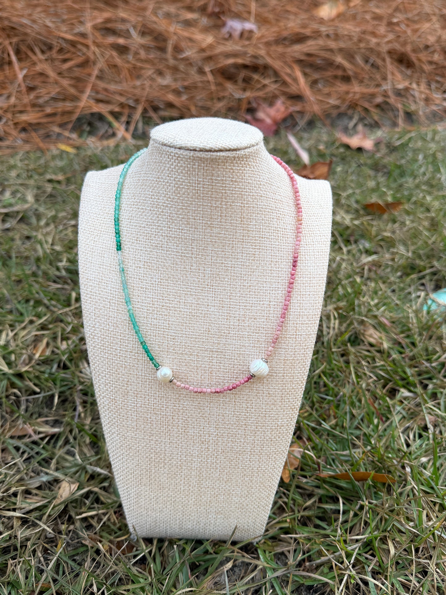 Textile product on a mannequin head with visible stitching, placed on grass.