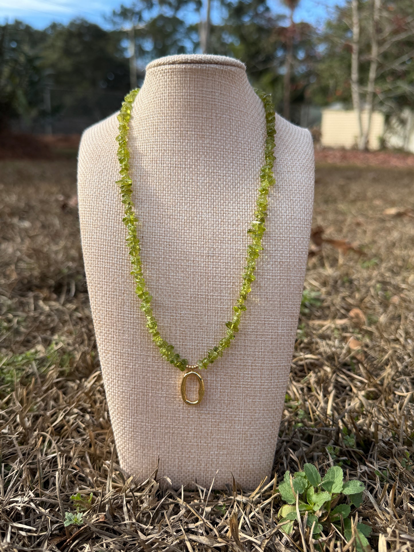 Necklace on a beige display stand with a blurred natural background