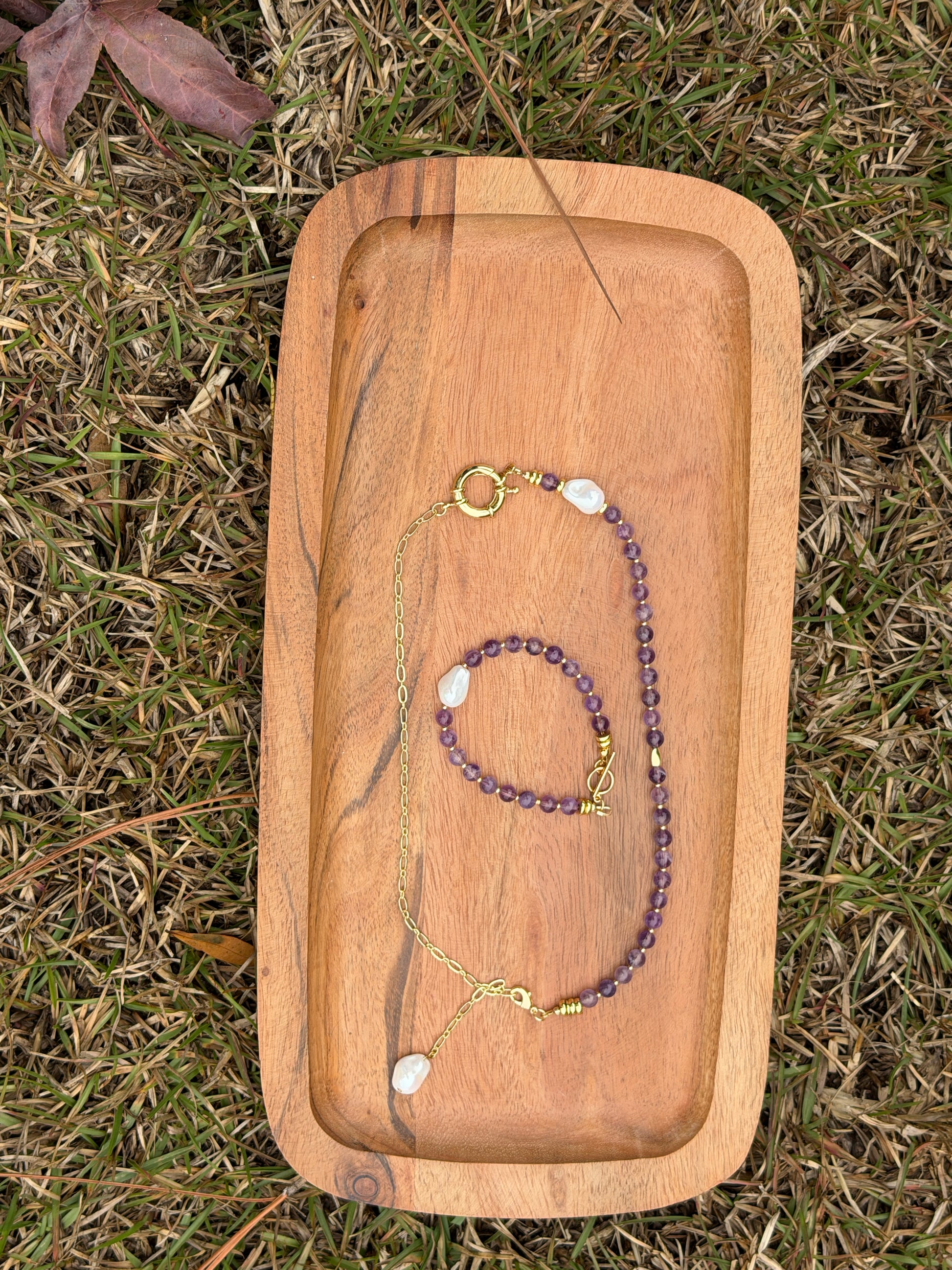 Amethyst and pearl set on a wooden tray outdoors