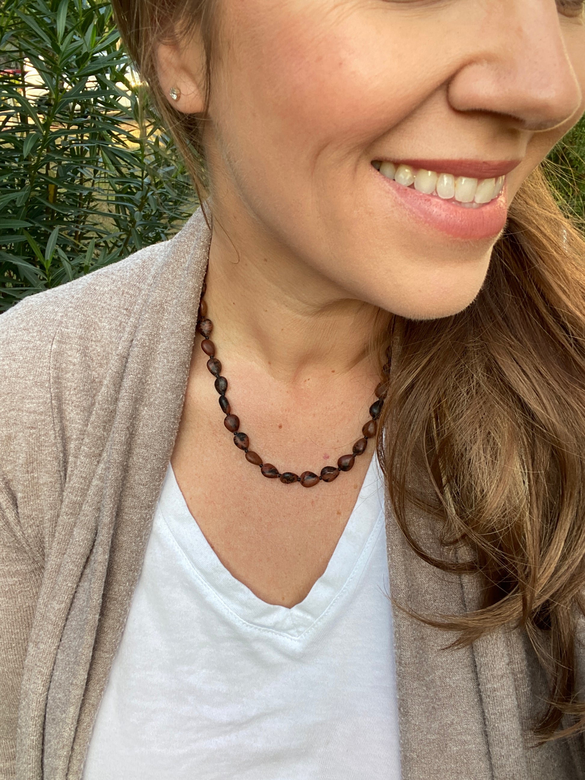 Woman wearing a beaded necklace with a neutral background