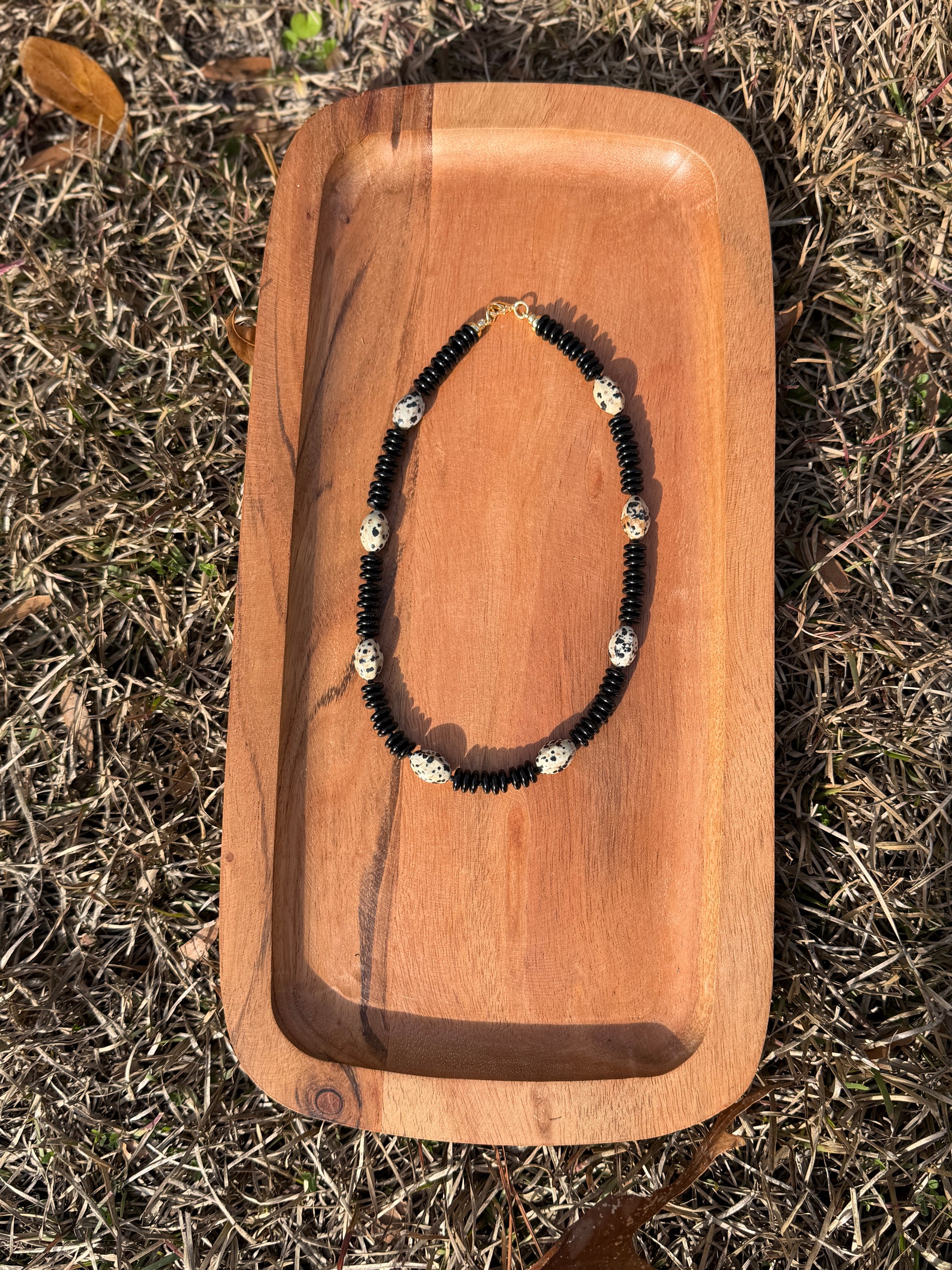 Necklace on a wooden tray with grass in the background